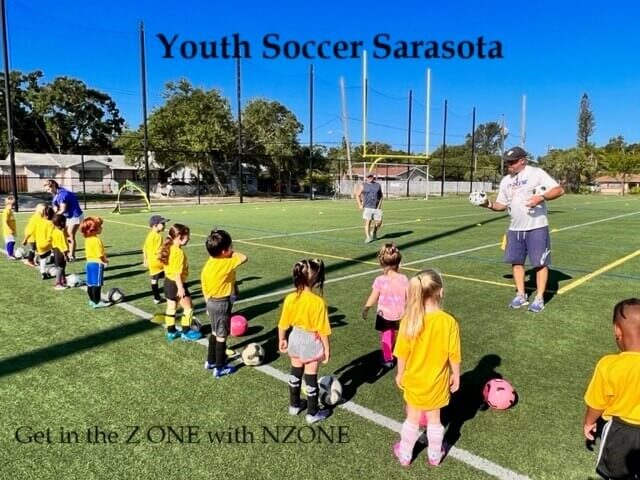 A dynamic scene of youth soccer in Sarasota, featuring young athletes engaged in a spirited match on a green field.